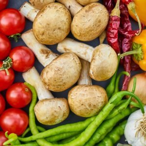 A vibrant assortment of fresh vegetables and mushrooms arranged in a flat lay.