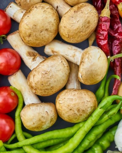 A vibrant assortment of fresh vegetables and mushrooms arranged in a flat lay.